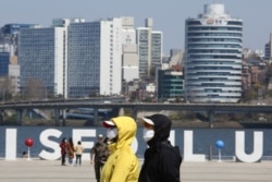 People wearing face masks to help protect against the spread of the new coronavirus walk at a park in Seoul, South Korea, April 8, 2020.