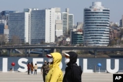 FILE - People wearing face masks to help protect against the spread of the new coronavirus walk at a park in Seoul, South Korea, April 8, 2020.