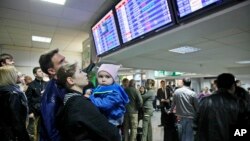 FILE - Travelers check a departures board at Borispol International Airport, near Kyiv, Ukraine.