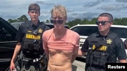 Ryan W. Routh, suspected of attempting to assassinate former President Donald Trump, stands handcuffed between two Martin County deputies after his arrest near Palm City, Fla., Sept. 15, 2024. (Martin County Sheriff's Office/Handout via Reuters)