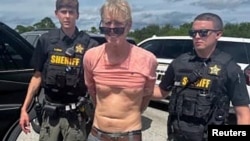 Ryan W. Routh, suspected of attempting to assassinate former President Donald Trump, stands handcuffed between two Martin County deputies after his arrest near Palm City, Fla., Sept. 15, 2024. (Martin County Sheriff's Office/Handout via Reuters)