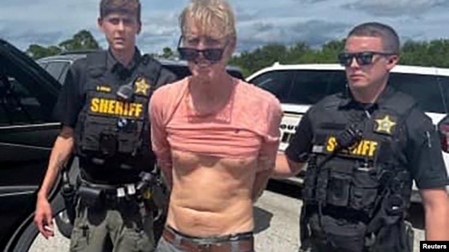 Ryan W. Routh, suspected of attempting to assassinate former President Donald Trump, stands handcuffed between two Martin County deputies after his arrest near Palm City, Fla., Sept. 15, 2024. (Martin County Sheriff's Office/Handout via Reuters)