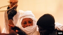 L’ancien président tchadien Hissène Habré se débat, tenu par deux gendarmes, lors d’une comparution au Palais de Justice à Dakar, Sénégal, 20 juillet 2015.