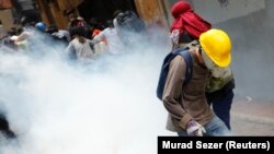 Para demonstran anti-pemerintah berjalan menghindari gas airmata yang ditembakkan untuk membubarkan mereka, dalam peringatan setahun protes anti-pemerintah di pusat kota Istanbul (31/5).