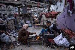 Anggota keluarga Al-Rabaya berbuka puasa saat bulan suci Ramadhan di luar rumah mereka yang hancur akibat serangan udara Israel di Rafah, Jalur Gaza, Senin, 18 Maret 2024. (Foto: AP)