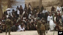 Afghan National Army soldiers keep watch as Afghans gather outside a U.S. base in Panjwai district Kandahar province, March 11, 2012. 