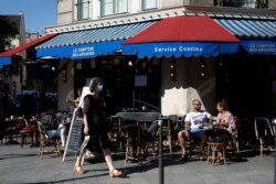 People sit on a terrace in Paris, Tuesday, June 2, 2020. Parisians who have been cooped up for months with take-out food and coffee will be able to savor their steaks tartare in the fresh air and cobbled streets of the City of Light once more.