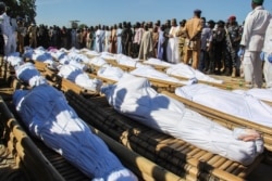 FILE - Mourners attend the funeral of 43 farm workers in Zabarmari, about 20km from Maiduguri, Nigeria, Nov. 29, 2020, after they were killed by Boko Haram fighters in rice fields near the village of Koshobe.