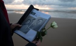Billie Bishop, from San Jose, California, holds a photo of his uncle, WWII soldier Billie Bishop, as he prepares to lay a rose in the sea during a D-Day 76th anniversary ceremony in Saint Laurent sur Mer, Normandy, France, June 6, 2020.