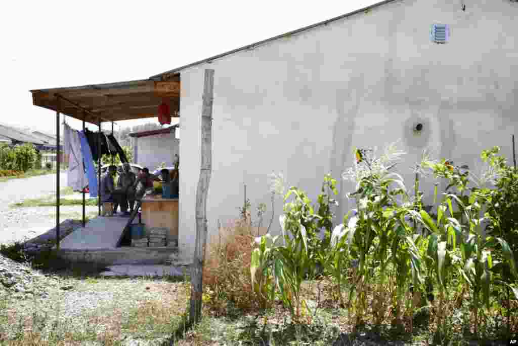 A group of men sit on a porch in this refugee camp playing backgammon. (Yuli Weeks for VOA)