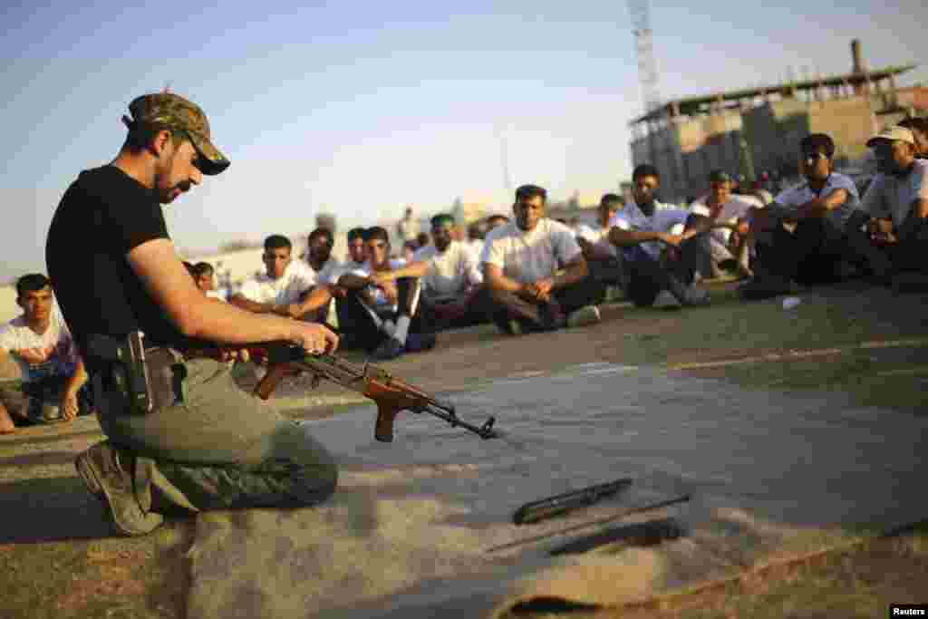 Shi'ite volunteers from the Supreme Islamic Iraqi Council watch a man handle a weapon during a training in Najaf, June 24, 2014. U.S. Secretary of State John Kerry held crisis talks with leaders of Iraq's autonomous Kurdish region on Tuesday urging them t