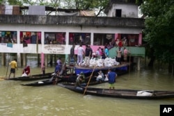 FILE - Flood affected people receive relief material at Companygonj in Sylhet, Bangladesh, Monday, June 20, 2022. (AP Photo/Mahmud Hossain Opu)