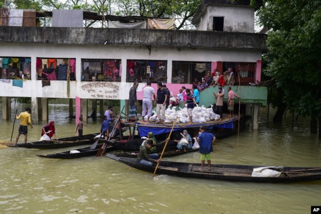 FILE - Flood affected people receive relief material at Companygonj in Sylhet, Bangladesh, Monday, June 20, 2022. (AP Photo/Mahmud Hossain Opu)