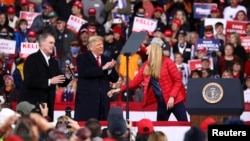 U.S. President Donald Trump applauds as he hosts a campaign event with U.S. Republican Senators David Perdue (L) and Kelly Loeffler (R) at Valdosta Regional Airport in Valdosta, Georgia, U.S., December 5, 2020.