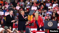 Presiden AS Donald Trump bertepuk tangan saat ia kampanye dengan Senator Republik AS David Perdue (kiri) dan Kelly Loeffler (kanan) di Bandara Regional Valdosta di Valdosta, Georgia, AS, 5 Desember 2020. (Foto: REUTERS/Dustin Chambers)