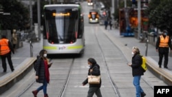 People wearing face masks cross the normally busy Burke Street Mall in Melbourne.