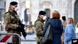 Italian soldiers wearing sanitary masks patrol Duomo square in downtown Milan, Italy, Monday, Feb. 24, 2020. 