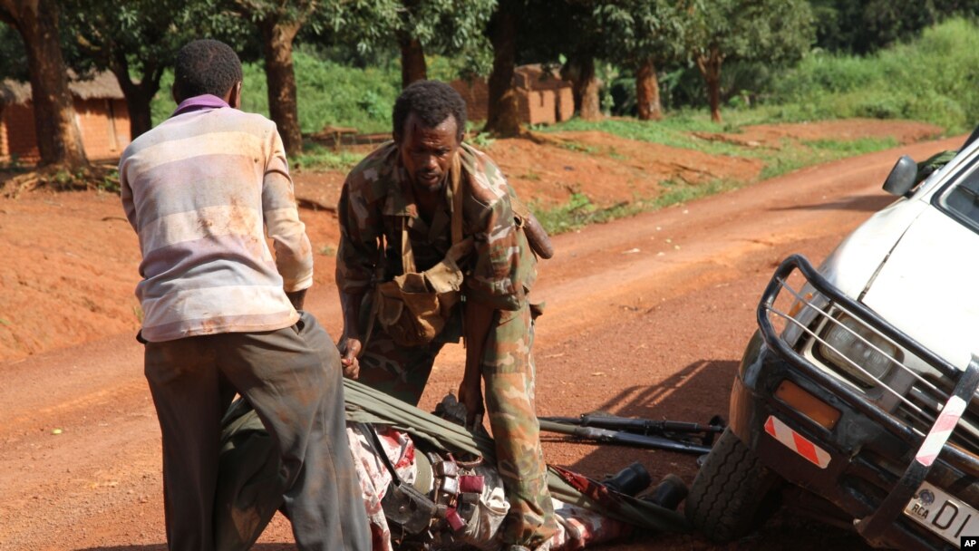 In this Sept. 16, 2013 photo, A Gabonese soldier from a regional Central African peacekeeping force helps collect the bodies of rebels who were reportedly killed by armed villagers in Njoh, Central African Republic. 