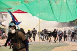 Manifestantes corren durante una ofensiva de las fuerzas de seguridad en el municipio de Hlaing de Rangún, Myanmar, el 17 de marzo de 2021.