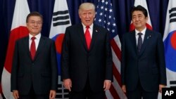 FILE - President Donald Trump poses for a picture with Japanese Prime Minister Shinzo Abe, right, and South Korean President Moon Jae-in ahead of a security meeting in Hamburg, Germany, July 6, 2017.