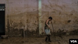 A Thai man is seen clearing mud from the streets of Mae Sai, Thailand, following flooding Sept. 22, 2024. (Tommy Walker/VOA)