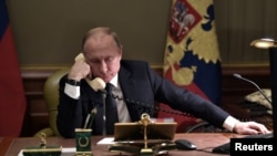 FILE - Russian President Vladimir Putin sits at a table during a telephone conversation in St. Petersburg, Russia, Dec. 15, 2018.