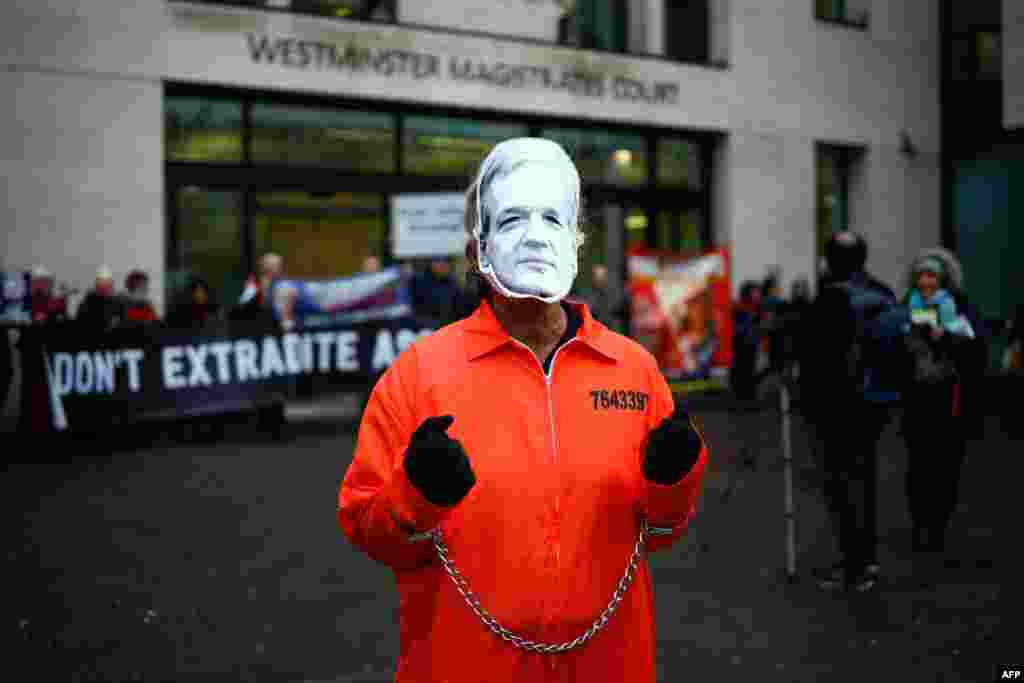 A protester wears a mask of Wikileaks founder Julian Assange and prison overalls as he stands outside Westminster Magistrates Court in London.