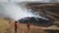 FILE - A man gestures as smoke rises from a burning farmland targeted by what activists said were airstrikes by forces loyal to Syria's President Bashar al-Assad in Maarshmarin village in Idlib countryside, May 24, 2015. 