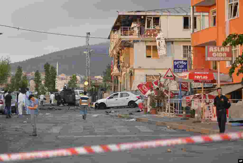 Turkish police officers work near the site of an explosion at a police station, seen right, in Istanbul&#39;s Sultanbeyli neighborhood, early Monday, Aug. 10, 2015.