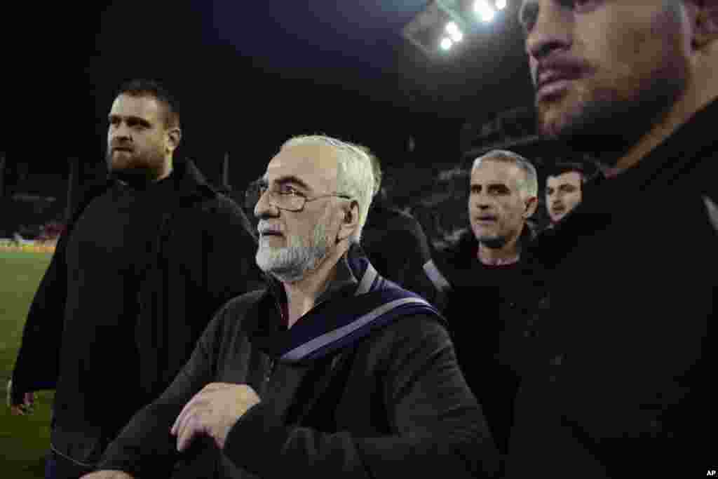 Mai kungiyar PAOK, Ivan Savvidis, rataye da bindiga a kunkuminsa, tare da masu gadinsa, a lokacin da ya kutsa cikin filin wasa a karawarsu da AEK Athens ranar lahadai a birnin&nbsp; Thessaloniki. Sau biyu Savvidis yana kutsawa cikin filin a lokacin wasa. Jami&#39;an AEK sun yi zargin cewa Savvidis yayi barazana ga alkalin wasan a kutsawarsa ta farko, kafin masu gadinsa su janye shi. A karo na biyu an ga bindiga a rataye a kunkuminsa.(InTime Sports via AP)