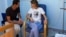 This photo posted Aug 8, 2018 on the official Facebook page of the Syrian Presidency, shows President Assad sitting next to his wife Asma Assad with an IV in her left arm in what appears to be a hospital room, in Syria. 