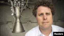 FILE - Rocket Lab CEO Peter Beck poses alongside a Rutherford rocket engine in Auckland, New Zealand, Oct. 20, 2015. 
