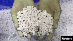 Pekerja di sebuah pabrik Kalbe Farma memegang setumpuk tablet di Cikarang. (Foto: Dok)