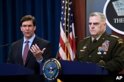 FILE - Defense Secretary Mark Esper, left, standing with Joint Chiefs​ Chairman Gen. Mark Milley, right, speaks during a news conference at the Pentagon in Washington, Dec. 20, 2019.