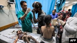 EDITORS NOTE: Graphic content / A surgeon and a physician check on a man and a child, both injured in Israeli bombardment, at a trauma ward at Nasser hospital in Khan Yunis in the southern Gaza Strip on October 24, 2023 amid the ongoing battles between Is