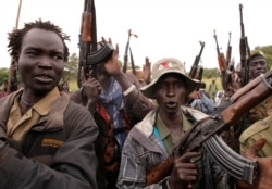 FILE - SPLA-IO rebels hold up guns in Yondu, South Sudan, Aug. 25, 2017.