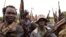 FILE - Caption SPLA-IO rebels hold up guns in Yondu, the day before an assault on government SPLA (Sudan People's Liberation Army) soldiers in the town of Kaya, on the border with Uganda, South Sudan, Aug. 25, 2017.