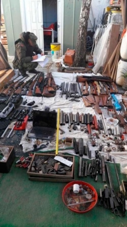 In this photo provided by the Argentine Ministry of Security, a police officer takes inventory a cachet of weapons seized by authorities at an undisclosed location in Argentina, June 26, 2019.