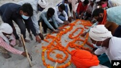 Family members and relatives pray after burying a person who died of reasons other than COVID-19 in a shallow sand grave on the banks of river Ganges in Prayagraj, India, May 16, 2021.