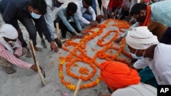 Warga India berdoa usai menguburkan warga korban COVID-19 di tepi Sungai Gangga di kota Prayagraj (16/5).