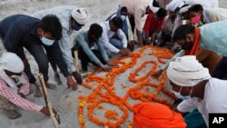 Family members and relatives pray after burying a person who died of reasons other than COVID-19 in a shallow sand grave on the banks of river Ganges in Prayagraj, India, May 16, 2021.