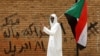 FILE - A protester makes a victory sign as he carries a Sudanese flag in front of the Defense Ministry in Khartoum, Sudan, April 19, 2019. 