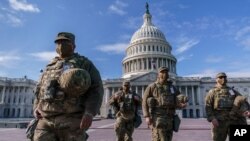 Las tropas de la Guardia Nacional reciben armas y municiones fuera del edificio del Capitolio de EE.UU., el domingo 17 de enero de 2021.