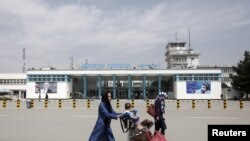 FILE - Afghan passengers walk in front of Hamid Karzai International Airport in Kabul, Afghanistan, March 29, 2016. 