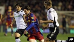 Lionel Messi na FC Barcelona yana kokarin ketawa da kwallo a tsakanin Ever Banega da Marius Stankevicius na Valencia a karawarsu ta ranar 2 Maris 2011.