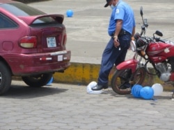 Un policía revienta globos usados en una conmemoración de familiares de manifestantes en el aniversario del inicio de la crisis política en Nicaragua de 2018, en Masaya el 20 de abril de 2020. Foto cortesía de Noel Miranda.