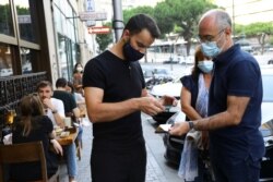 Restaurant staff checks a digital vaccination certificate at the entrance, on the day that Portugal's government imposed stricter rules in an attempt to bring under control a surge of COVID-19 cases, in Porto, Portugal, July 10, 2021.