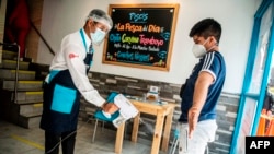 Un mesero desinfecta a un cliente al entrar a un restaurante el Lima. La famosa cocina peruana ha reactivado sus operaciones tras cuatro meses de confinamiento.