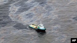 This photo taken Nov. 18, 2011 and released by Rio de Janeiro's government, shows an aerial view of a boat crossing an area of an oil spill in an offshore field operated by Chevron at the Bacia de Campos, in Rio de Janeiro state, Brazil.