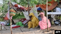 (FILE) People stranded in an inundated area in Tokar in the Red Sea State following recent heavy flooding in eastern Sudan, sit in front of their tent on September 5, 2024.